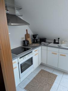 a kitchen with white cabinets and a stove top oven at Apartment am Park Anklam in Anklam