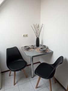 a table with two chairs and a vase on it at Apartment am Park Anklam in Anklam