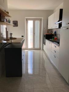 a large kitchen with white cabinets and a large window at Villa Maria Giuseppina a San Benedetto del Tronto in Monteprandone +15 photos