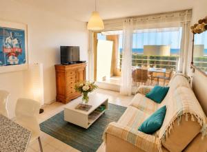 a living room with a couch and a tv at Lagune Azur – Séjour cosy vue mer piscine Wi-Fi in Sète