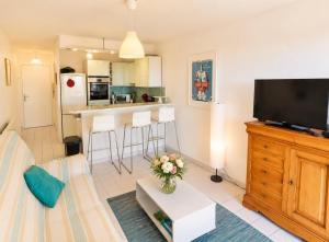 a living room with a couch and a tv at Lagune Azur – Séjour cosy vue mer piscine Wi-Fi in Sète