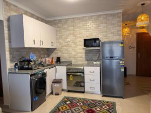 a kitchen with a stainless steel refrigerator and white cabinets at عائلي ومريح in Zāwiyat al ‘Awwāmah