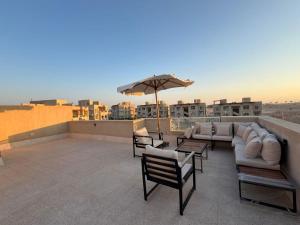 a patio with furniture and an umbrella on a roof at عائلي ومريح in Zāwiyat al ‘Awwāmah