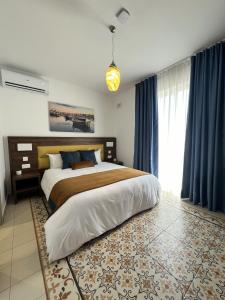 a bedroom with a large bed with blue curtains at Seaview Marsaxlokk Apartment Eye of Osiris in Marsaxlokk