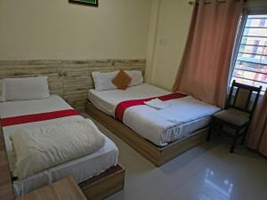 two beds in a room with a window and a chair at Kutumba Home in Bhairāhawā