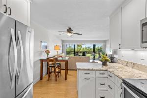 a kitchen with white cabinets and a dining room at Keauhou Punahele#D-206 in Kailua-Kona