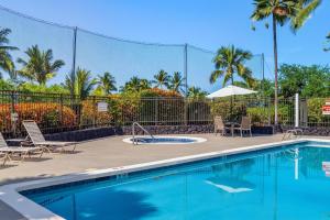 a swimming pool with chairs and an umbrella at Keauhou Punahele#D-206 in Kailua-Kona