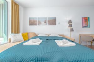 a blue bed with two towels on top of it at Apartment TOMI - Olivia Residence in Trnávka