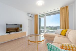 a living room with a couch and a large window at Apartment TOMI - Olivia Residence in Trnávka