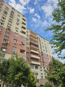 a tall apartment building with trees in the foreground at Ganja Comfort Home in Ganja