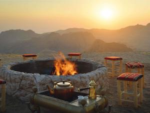 a fire pit in the middle of a desert with the sunset at Grand Mercure Petra in Wadi Musa