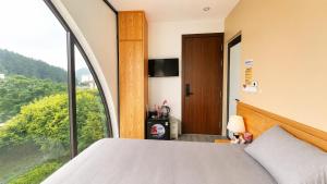 a bedroom with a bed and a large window at Gabi Boutique Hotel in Mộc Châu