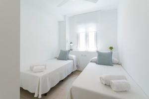 two beds in a room with white walls and blue pillows at AG LAS SIRENAS in Playa de Gandia +48 photos