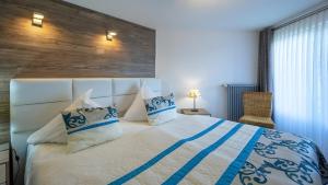 a bedroom with a large bed with blue and white pillows at Exclusiv Ferienwohnung Maarpanorama in Schalkenmehren +3 photos