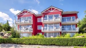 a red building with bushes in front of it at Exclusiv Ferienwohnung Maarpanorama in Schalkenmehren