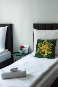 a bed with a green and white pillow and a table at Ajncla in Katowice