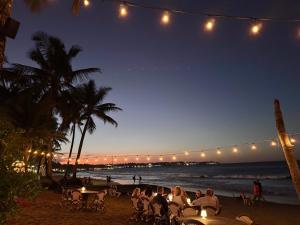 a group of people sitting at tables on the beach at night at La Curadiña - Encuentro Surf Hotel in Cabarete