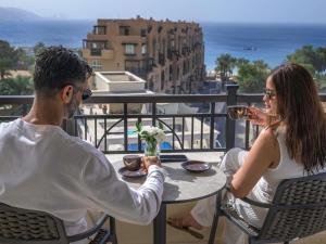 a man and a woman sitting at a table on a balcony at Mövenpick Resort & Residences Aqaba in Aqaba +264 photos