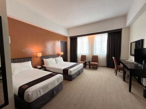 a hotel room with two beds and a desk at Hotel Seri Malaysia Lawas in Lawas