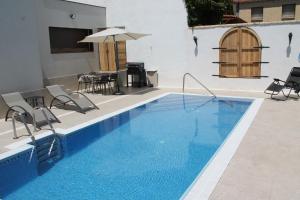 a pool with chairs and a table and an umbrella at La Alcoholera in Valtierra