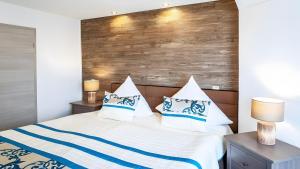 a bedroom with a bed with blue and white pillows at Exclusiv Apartment - Seepanorama in Schalkenmehren