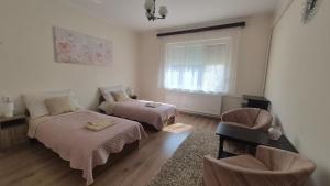a bedroom with two beds and a chair and a window at Akácfa Vendégház in Makó