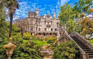 an old mansion with a staircase in front of it at Beach house with garden in Sintra