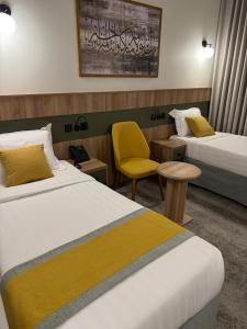 a hotel room with two beds and a yellow chair at HDN Hotel فندق هدن in Mecca