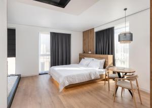 a bedroom with a bed and a table and some windows at Lumen Living in Kyiv