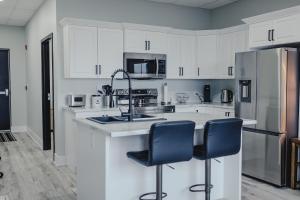 a kitchen with white cabinets and a sink and two chairs at Falkenberg Business Centre and Suites in Botwood