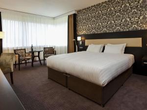 a hotel room with a large bed and a table at Mercure Antwerp City South in Antwerp