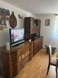 a living room with a television on a wooden dresser at Stella apartman in Gabčíkovo