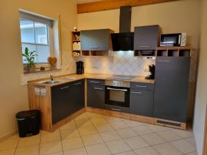 a kitchen with gray appliances and a sink and a window at Eifel Dream Wildeiche in Fleringen +8 photos