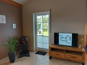a living room with a flat screen tv on a wooden stand at Eifel Dream Wildeiche in Fleringen