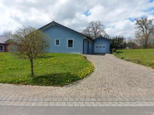 a blue house with a tree and a brick driveway at Eifel Dream Wildeiche in Fleringen