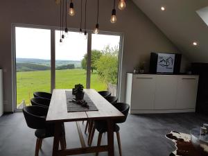 a dining room with a table and chairs and a large window at Eifel Dream Ardennenblick in Kobscheid