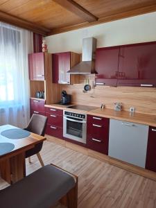 a kitchen with red cabinets and a table with a dining room at Ferienhaus Savannah in Schützen am Gebirge