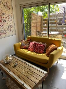 a yellow couch in a living room with a wooden coffee table at La maison du bonheur in Audenge