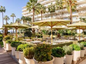 a row of tables with umbrellas and potted plants at Mondrian Cannes in Cannes
