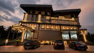 a building with three cars parked in front of it at Hotel Mulki International in Mūlki