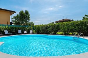 a large blue swimming pool with chairs and trees at La Casa di Gio - 2 Camere Singole in Campanella