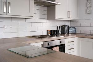 a kitchen with white cabinets and a counter top at Stoops Hall - 2 bed first floor apartment in Garstang