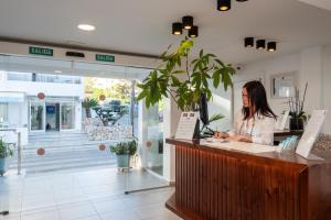 a woman sitting at a counter in a store at Hotel Chevy & Suites in Cala Ratjada +42 photos