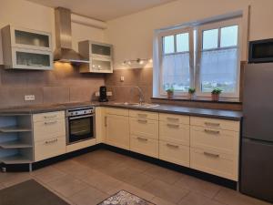 a kitchen with white cabinets and a stainless steel refrigerator at Eifel Dream Casa29 in Burbach