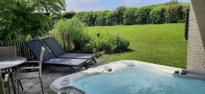 a hot tub in a yard with a table and a chair at Eifel Dream Casa29 in Burbach