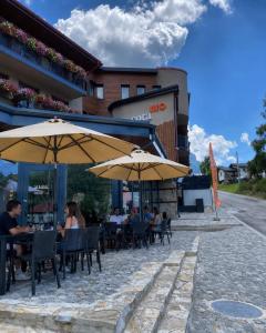 people sitting at tables with umbrellas in front of a building at Hotel COTA1110 in Beli Iskar