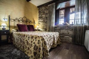 a bedroom with a bed and a stone wall at Apartamentos A Casa Nova in A Pontenova