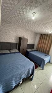 a bedroom with two beds with blue comforters at Kitnet aconchegante in Ouro Preto