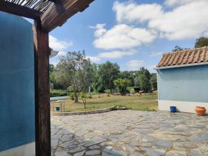 a stone patio with a blue building and a yard at Suite no campo in Cercal