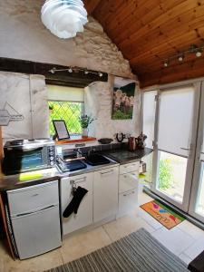 a kitchen with white cabinets and a stove top oven at Yr Hen Efail - Quirky Old Smithy cottage near forest walks, cycling & lakes in Garthbeibio